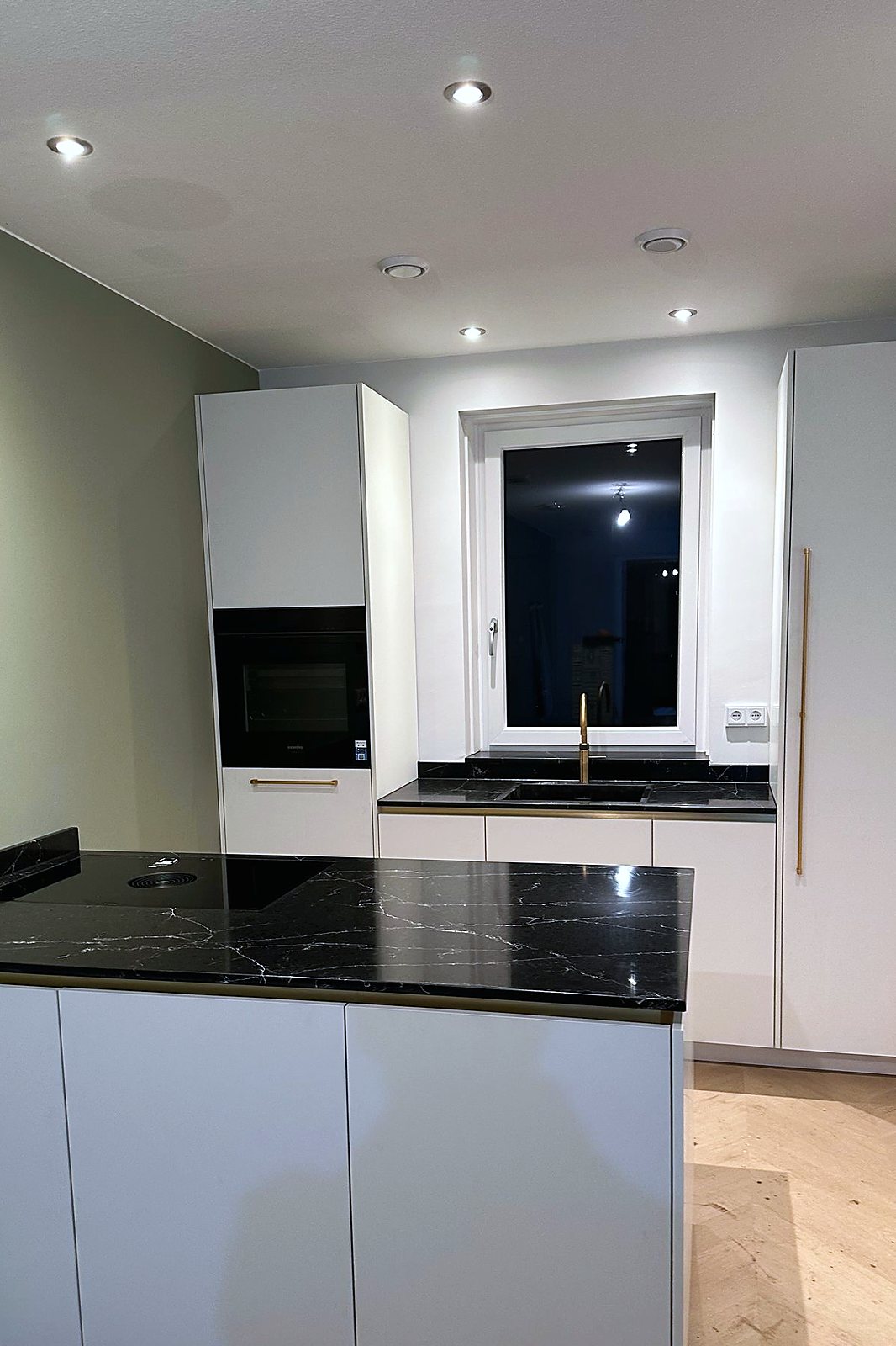 Overzicht van de witte keuken met marmerlook blad en aansluitend lager keukendeel, door Maatmakers Interieurbouw