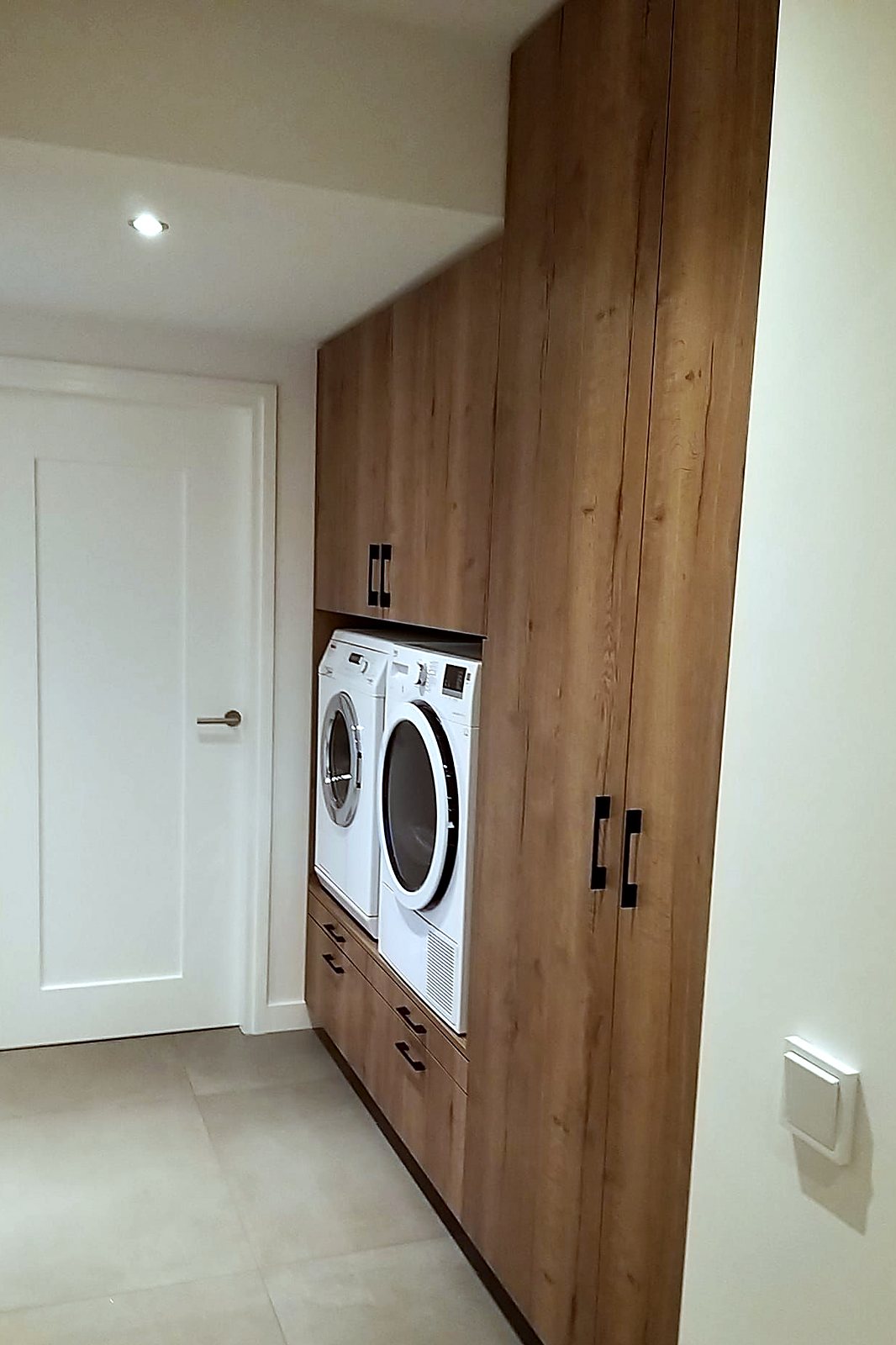 Bijkeuken in eiken met wasmachine en droger op werkhoogte ingebouwd in een hoge kastwand, door Maatmakers Interieurbouw